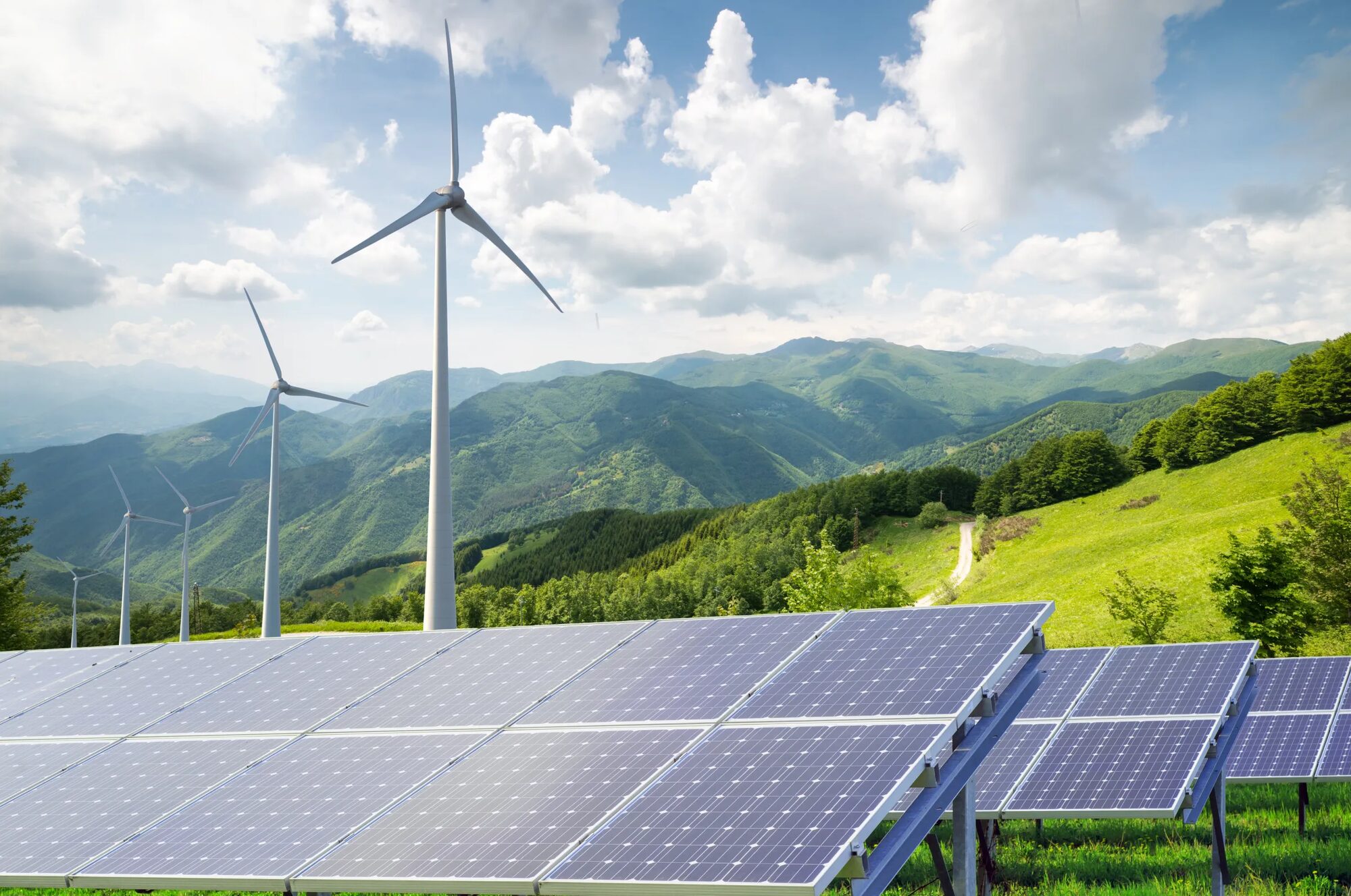 Solar panels and wind turbines across a mountain landscape